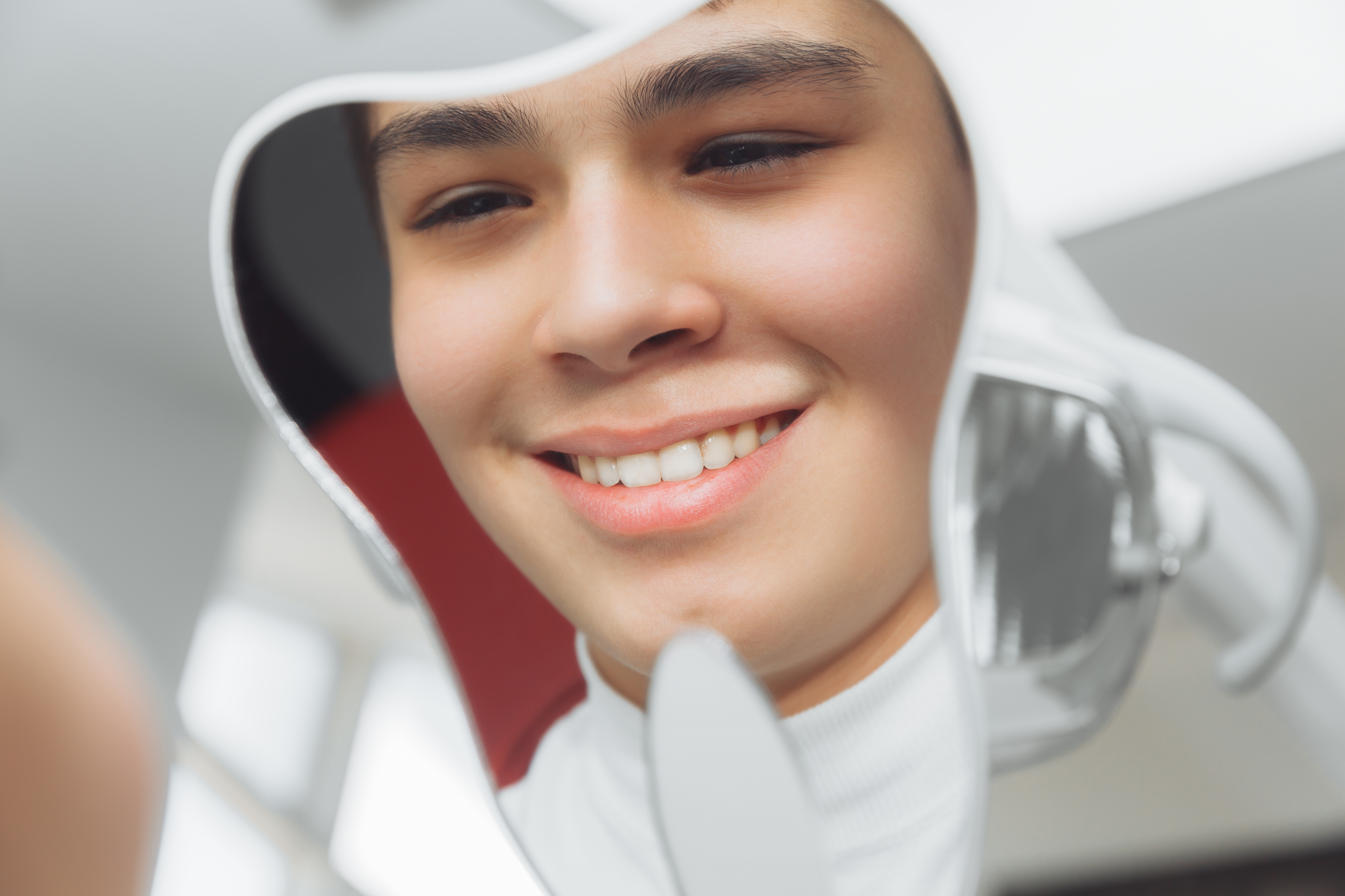 Patient smiling into a dental mirror during a restorative dentistry visit