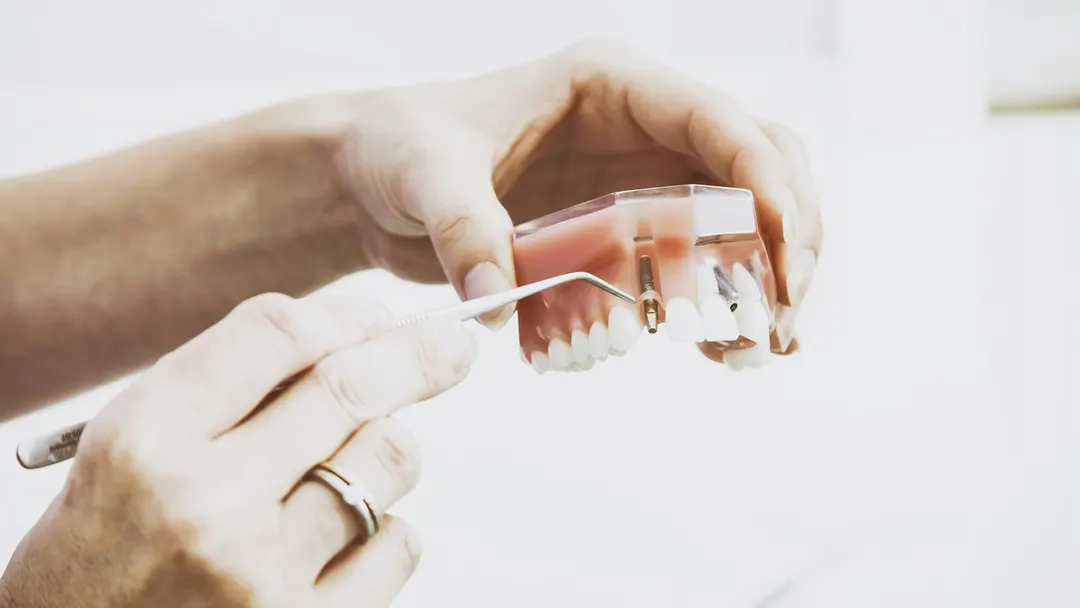 Dentist holding a tooth crown model while explaining a restorative treatment plan to a patient