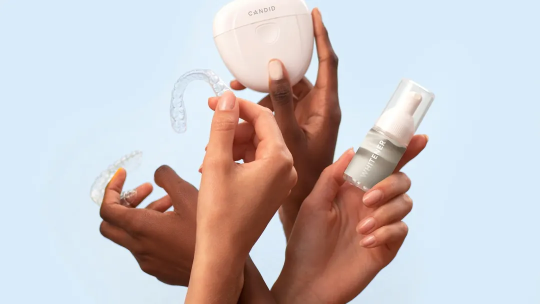 Hands holding a clear orthodontic aligner tray and storage case