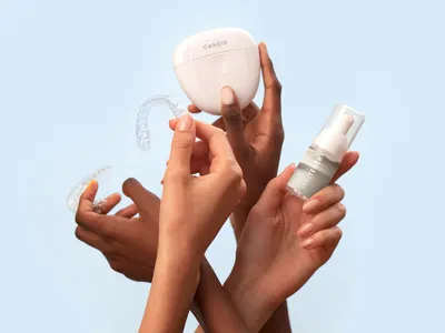 Hands holding clear orthodontic aligner trays and a storage case