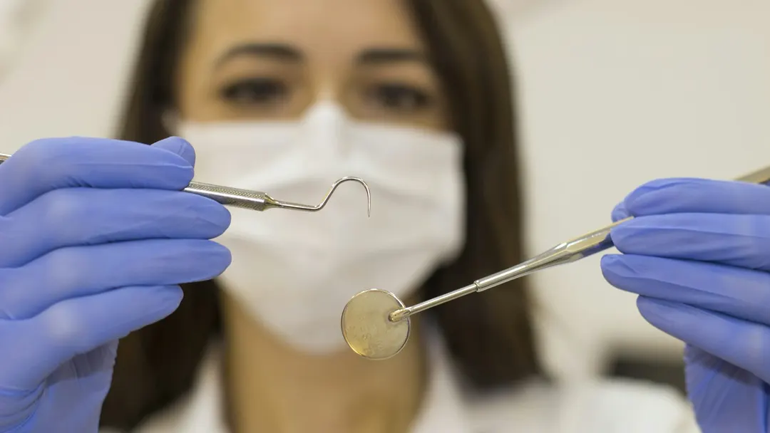 Dentist holding a periodontal probe and mirror during a gum health examination