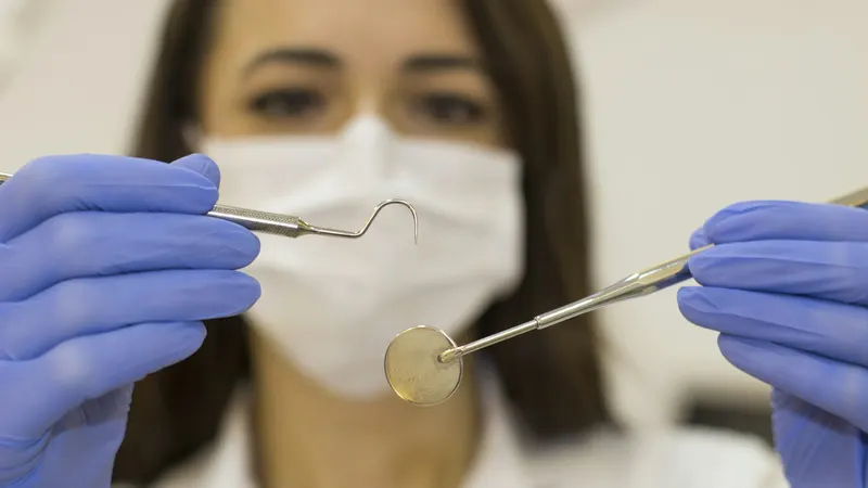 Dentist holding a periodontal probe and mirror during a gum health examination