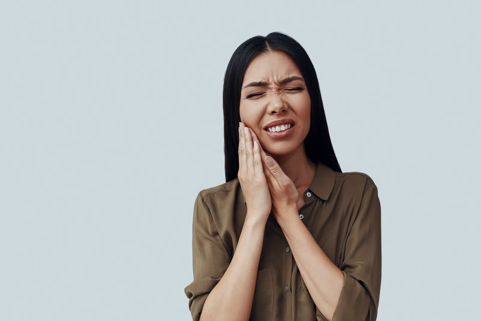 Woman experiencing toothache pain holding her jaw