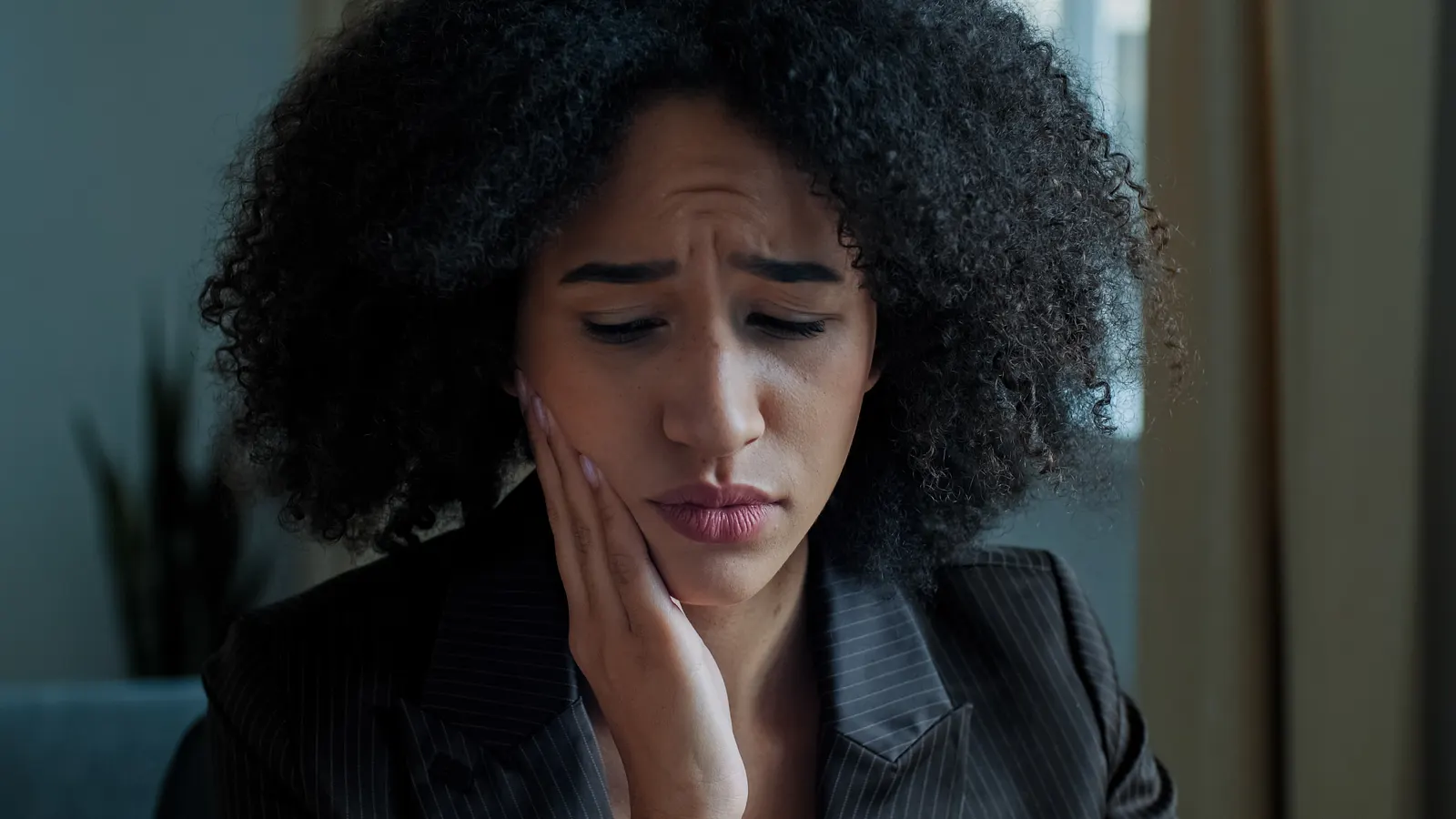 Woman holding her jaw in discomfort — emergency dental triage guide for West Covina